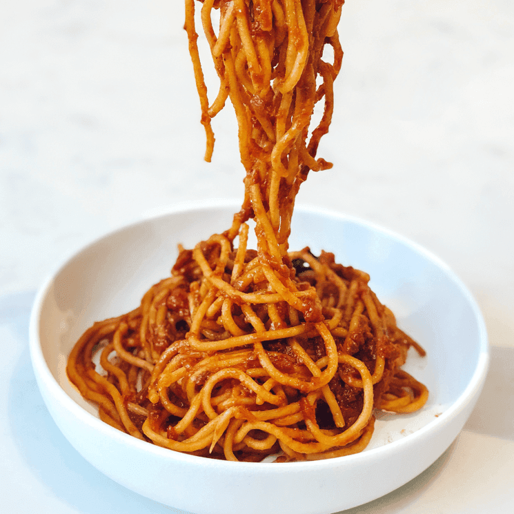 Spaghetti mit Tomatensauce werden auf einen Teller gehoben