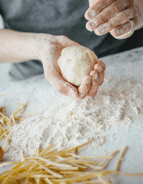 Hände formen Pizzateig auf bemehlter Fläche