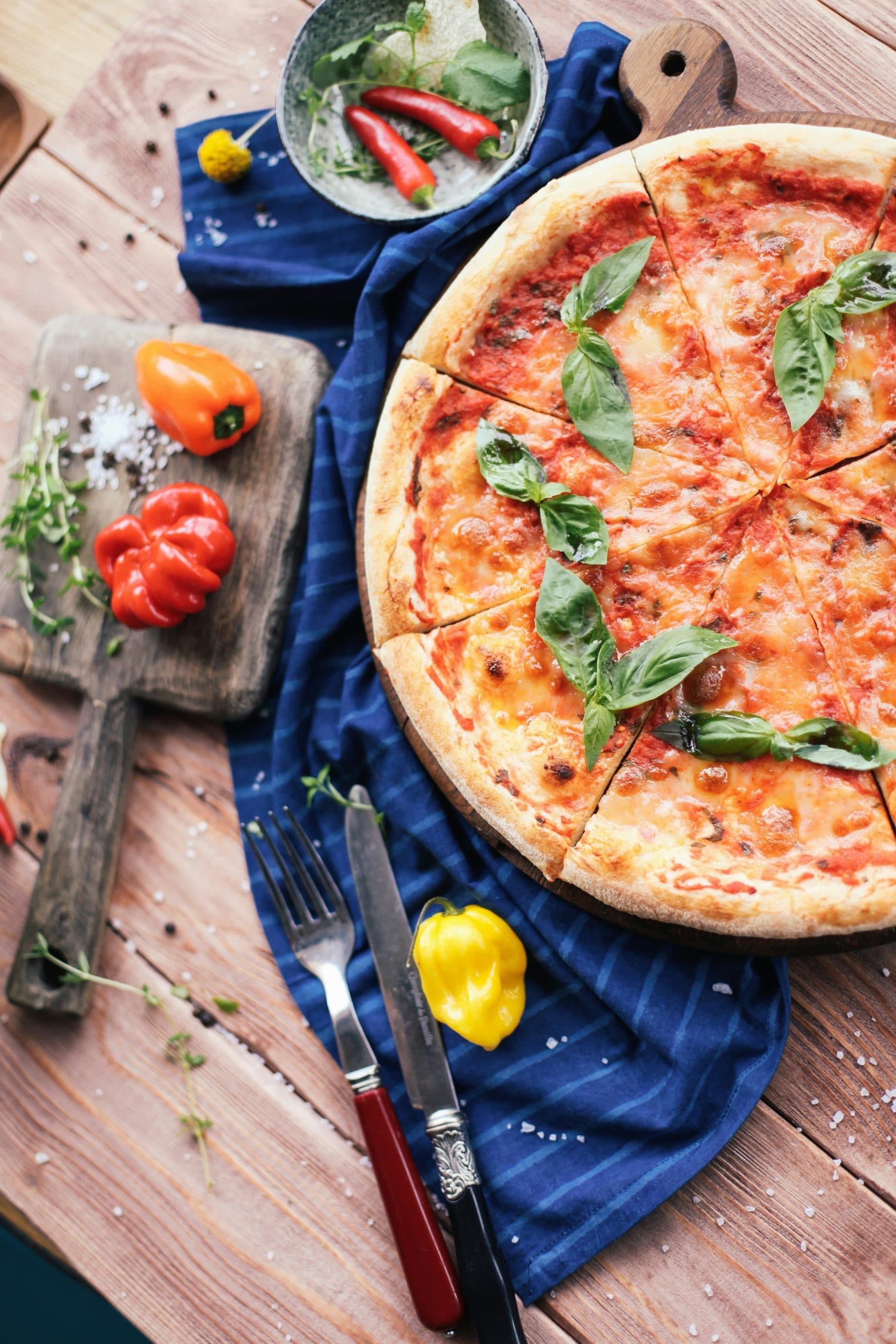 Frisch gebackene Pizza mit Basilikum auf einem Holzbrett